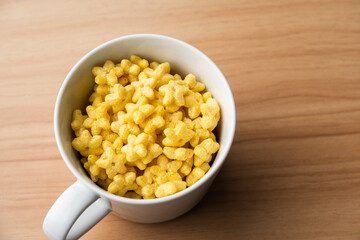 Yellow star shaped honey coated cereal inside a mug on a wooden background