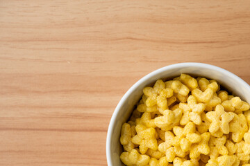 Star shaped honey coated cereal in a white bowl and wooden background.