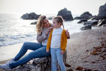 Happy family posing outdoor in the beach of the sea at spring time. woman with daughter have fun on vacation near ocean.  Travel, love, holidays concept - lifestyle