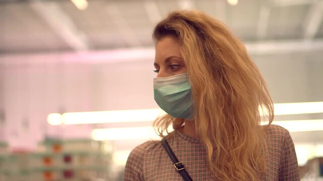 Woman Shopper Choosing Product In Hypermarket Store.Girl In Face Mask Shopping In Market On Covid19 Coronavirus Pandemic Quarantine Lockdown.Bayer In Medical Mask In Supermarket Avoid Self Distance