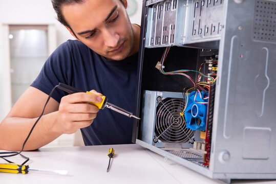 Young Man Repairing Computer At Home