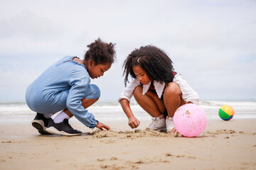 Fototapeta na wymiar Happy friendship. Happy vacation holiday. Happy two African American kids are building a sandcastle on the tropical beach and have fun together in summer. Relaxation in vacation in the summer concept.