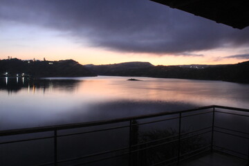 Vista de lago y montaña desde la terraza con mesa y sillas de madera al amanecer 
