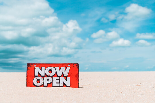 Now open sign board stand on sand summer beach background metaphor to time to travel relax tourism season with copyspace.