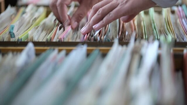 A businessman searching for financial and accounting documents in an office file cabinet