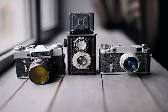 Three Old Reflex Cameras Isolated On Wooden Background vintage twin Lens reflex camera. Retro style medium format camera lens. Vintage film camera lens.