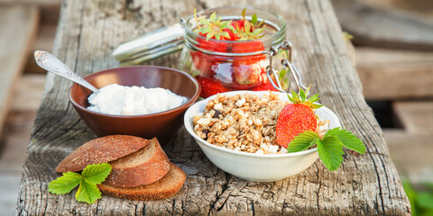 summer breakfast in a garden - cottage cheese, strawberry, muesli and milk. selective focus. style rustic