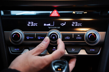 Hand turn on air conditioner dial button in a korean modern luxury car.