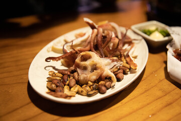 Korean traditional food to drink with Soju alcohol. Korean snack, octopus and peanuts on a white plate.