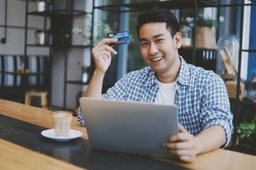 Asian man holding credit card in hand.