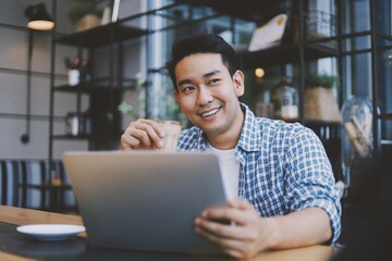 Asian man using laptop at home.