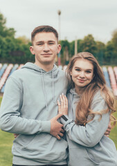 
Girl hugs a guy. A girl and a guy in identical sweatshirts at the stadium