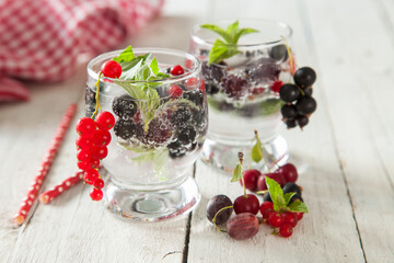 summer drink with berries and ice in a glass on a table, selective focus