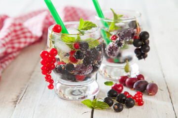 summer drink with berries and ice in a glass on a table, selective focus