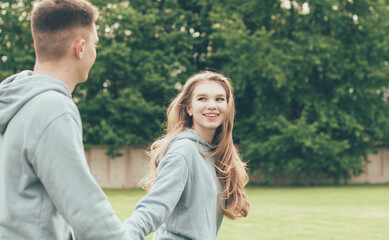 Fototapeta premium Girl leads a guy's hand,Girl leads a guy by the hand in the stadium and smiles