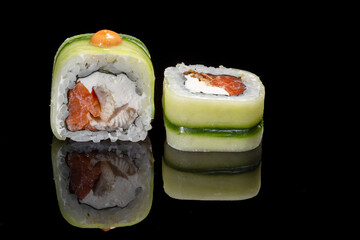 Sushi and rolls on a black mirrored background.