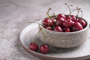 Red cherry berry  with drops of water at rustic ceramic plate at wooden background