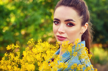 Close-up portrait of a young beautiful woman, against the background of summer nature.