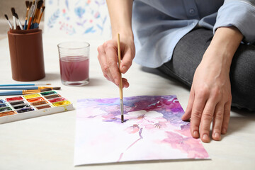 Fototapeta na wymiar Woman painting flowers with watercolor on floor, closeup