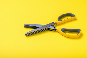 Scissors with yellow handles on a yellow background.