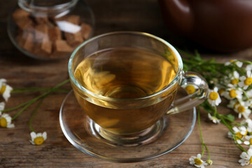Delicious chamomile tea in glass cup on wooden table