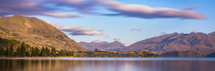 Fototapeta premium Mountain Lake Sunrise Landscape. Lake Wanaka New Zealand. Beautiful Morning Light Mountains Panorama Landscape Banner Background
