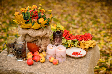 autumn still life with apples, clusters of mountain ash, autumn yellow leaves