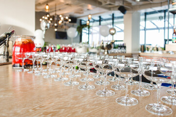 several rows of empty wide champagne glasses on a table in a banquet hall