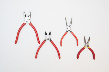 Different sizes of red pliers on a wooden background. Top view of repairing work tools on a wooden table.