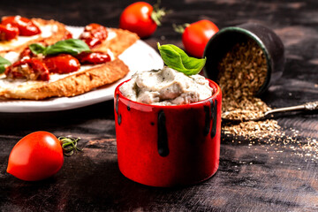 Fresh cream cheese spread with herbs in a bowl. Classic Italian antipasti bruschetta. Tomato Ricotta Bruschetta with sun dried tomatoes paste, olive oil and basil