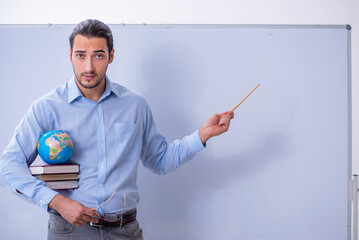 Young male geography teacher in front of whiteboard