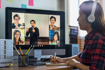 Closeup Asian woman hand writing lecture when online learning via video conference