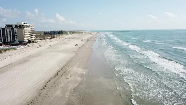 Aerial view moving up the beach and over the surf above Padre Island, Corpus Christi Texas