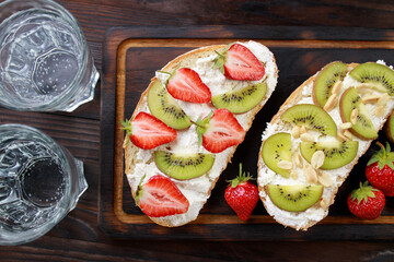 Strawberry and kiwi bruschettas with cottage cheese. Homemade healthy toast, delicious snack for kids. Sweet sandwiches with ripe summer berries and fruits