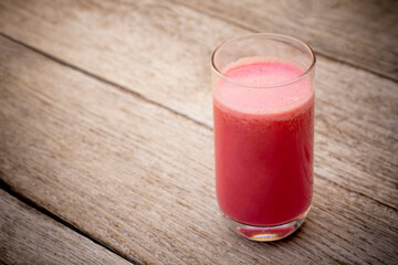 Glass of red smoothie milkshakes isolated on rustic wood table background.