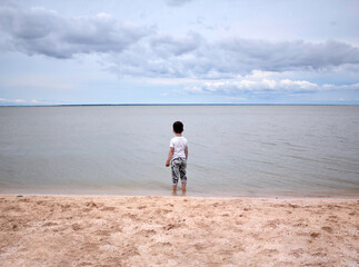 Little boy is looking at the sea in nasty day