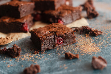 Tasty chocolate brownie with cherry. Pieces of cake on the table