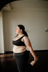 Obraz premium Home workout. Overweight woman doing stretching exercises on mat in her living room. Weight loss, activity and healthy lifestyle