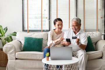 Asian woman teach senior use credit card and phone for online shopping