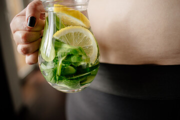 Detox and hydration. Overweight woman drinking infused water. Belly fat, weight loss, water balance and detoxification