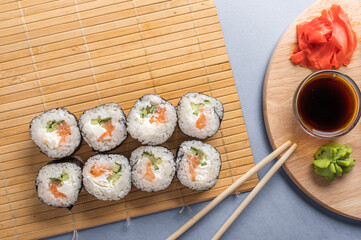Sushi rolls set served on bamboo mat. Blue background