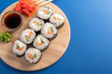 Fesh rolls with cucumber and salmon on a wooden board