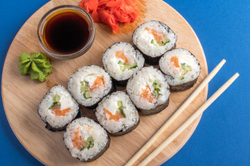 Fesh rolls with cucumber and salmon on a wooden board