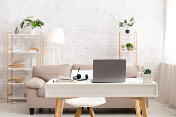 Workplace at home. Living room with desk, laptop and headphones
