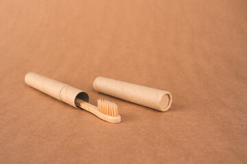 Close up of natural bamboo toothbrushe packed in reusable paper tube on brown kraft paper background with copy space. Sustainable lifestyle and plastic free concept, bathroom essentials, mockup