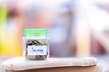 Coins in clear glass jars. There is a lid on light green bottle. Many coins in jars and labels were written to be 