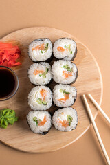 Sushi rolls set served on wooden board. Beige background