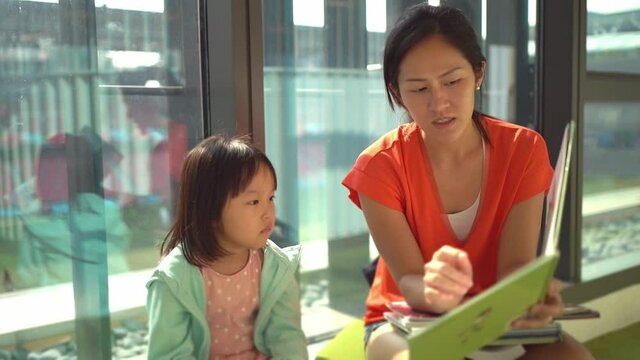 4K Slow Motion of Asian Parent and Child reading at the library