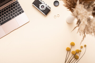 Autumn season fall concept. Top view of laptop, vintage camera, yellow leaves background. Minimal composition.