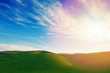 Naklejka na ściany i meble Green sloping meadows with blue sky